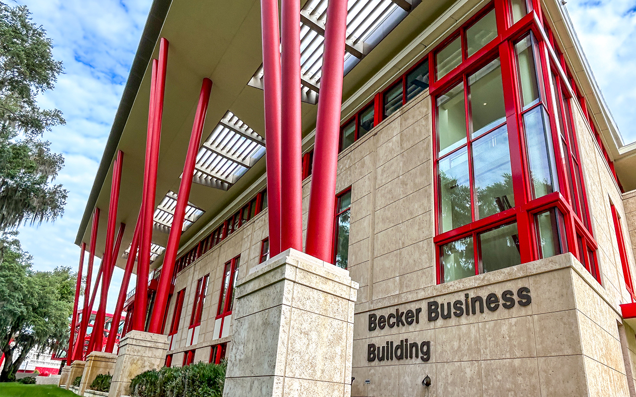Low angle exterior photo of the Becker Business Building against a bright blue sky.