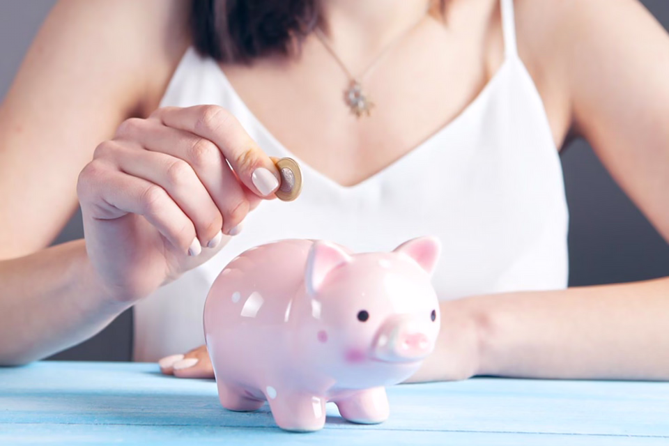 Woman putting coin in piggy bank