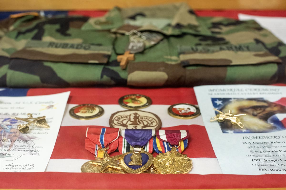various items, including a uniform, cross necklace, medals and memorials. 
