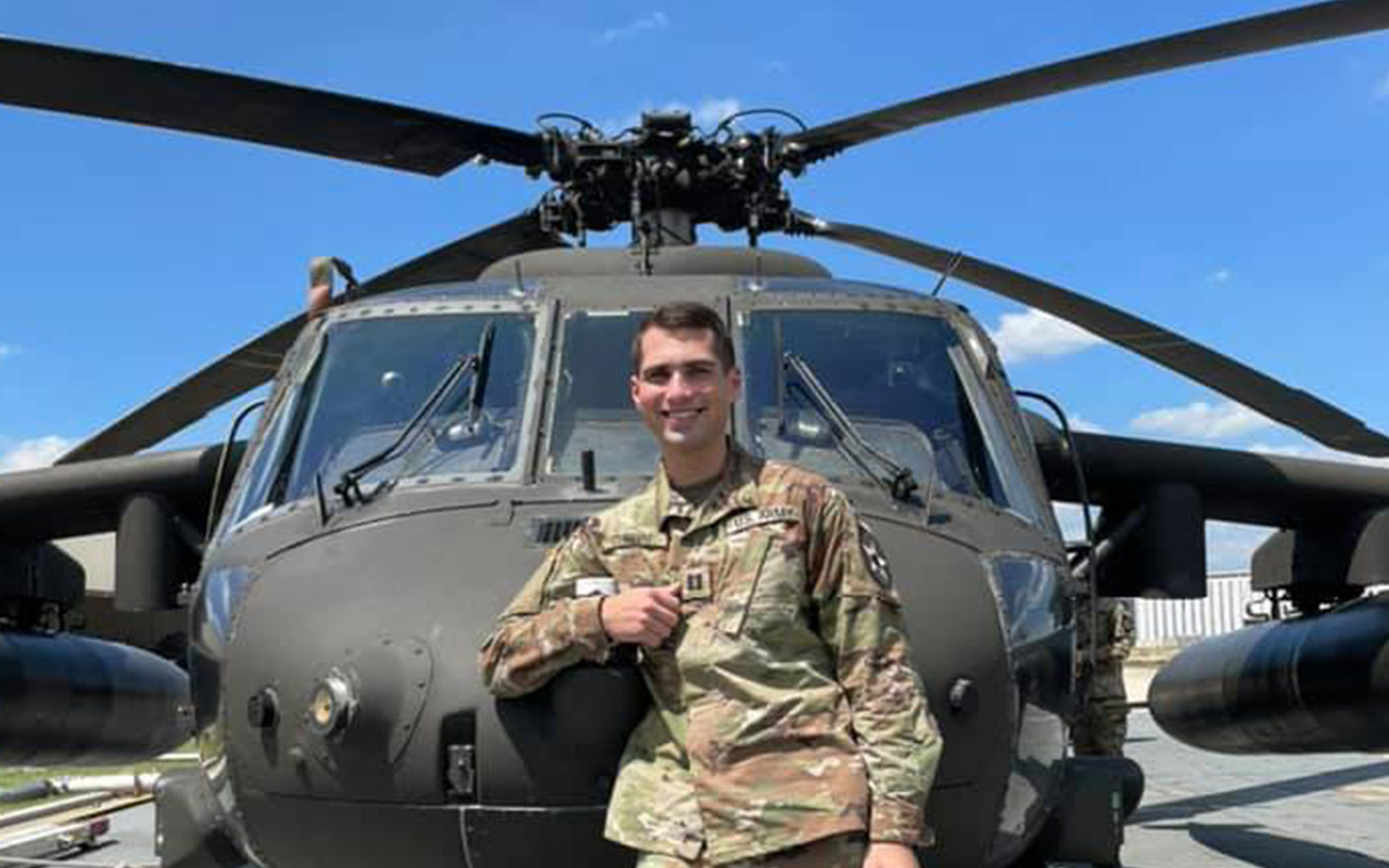 CPT Pedro Cuervo '17 poses in front of an Apache attack helicopter
