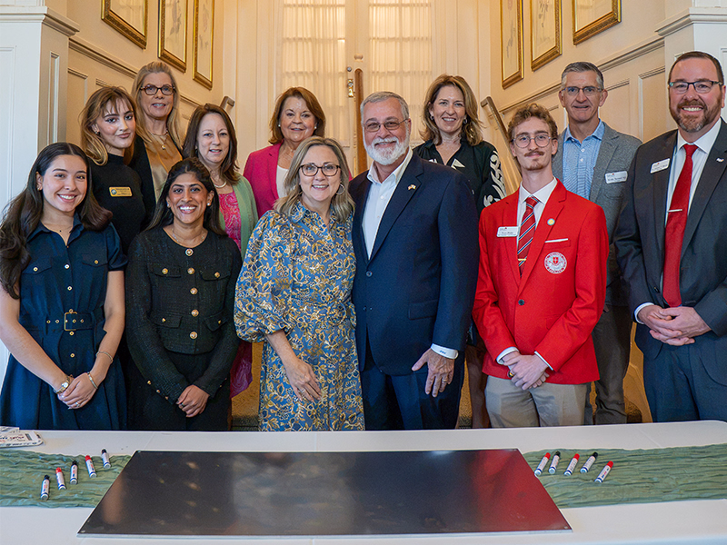 Select guests stand at the ceremonial Greenhouse Raising metal beam, ready to sign.