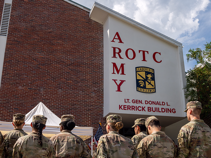 ROTC cadets stand in front of the newly dedicated ROTC building, with the words 