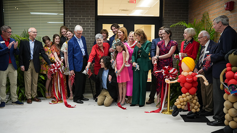 Members of the Roberts family and others cutting a ribbon to celebrate the completion of The Roberts Academy Middle School Expansion project.