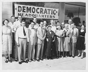 A group of people posing for a photo in front of a sign reading "Democratic Headquarters"