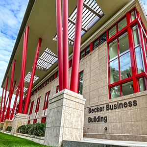 Low angle exterior photo of the Becker Business Building against a bright blue sky.