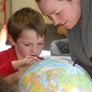 teacher and student looking at globe