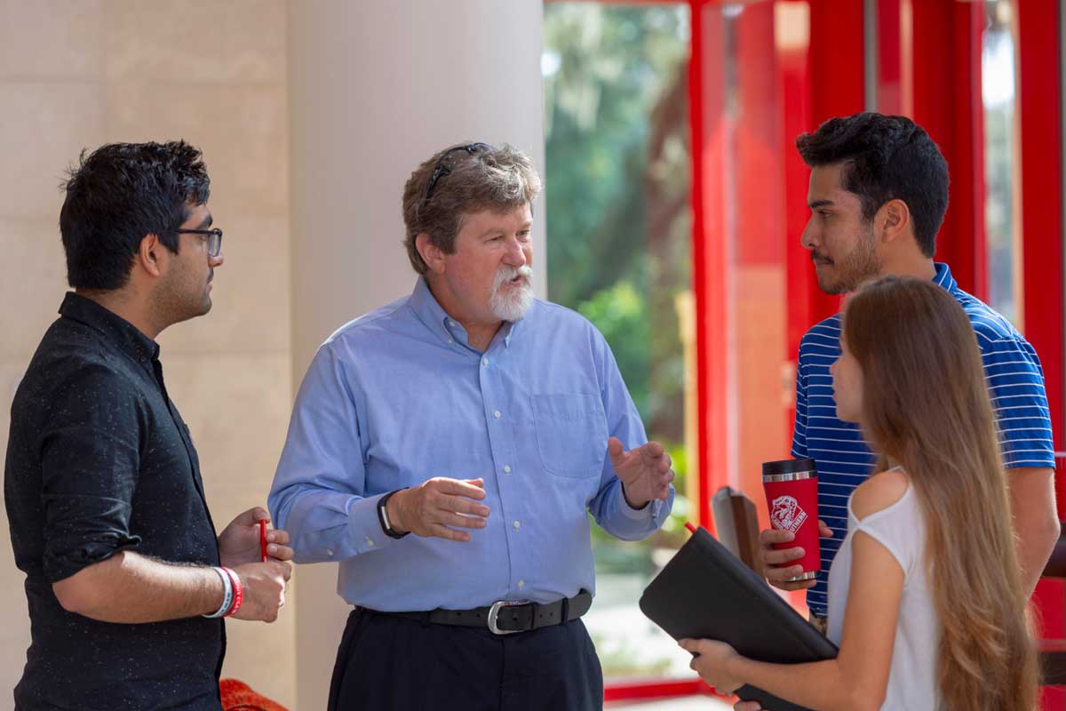 A professor speaking with three students