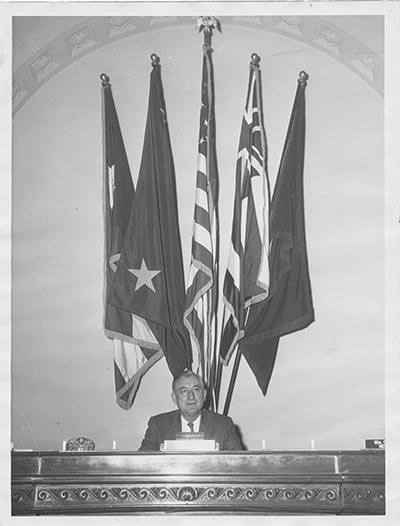 James Haley sitting at a desk in front of several flags