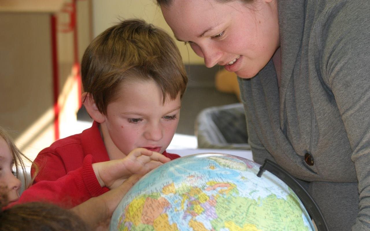 teacher and student looking at globe
